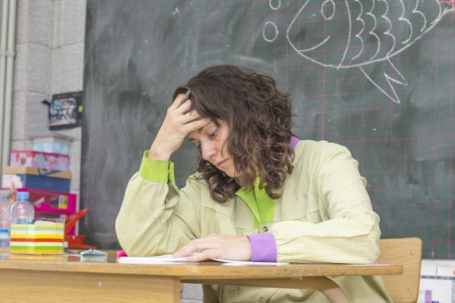 Tired And Stressed Teacher In Classroom At School.