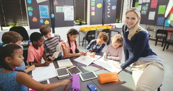 Teacher helping schoolgirl with her homework in classroom